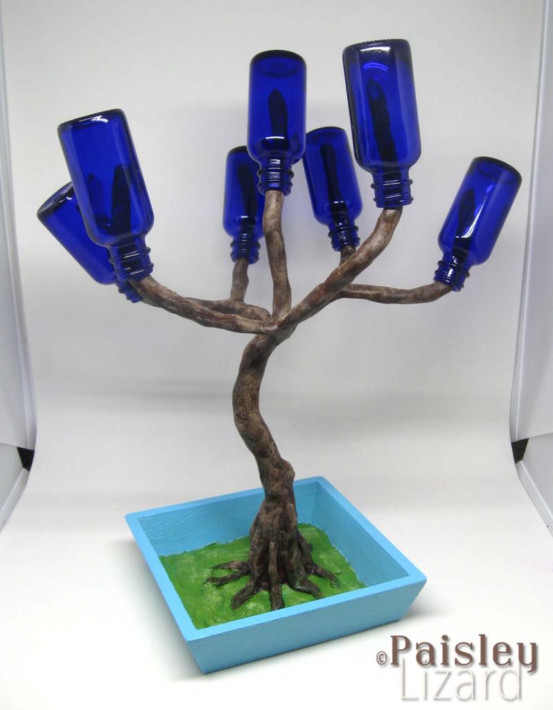 Miniature blue bottle tree in light box.