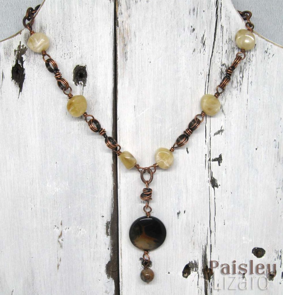 Brown agate beads and copper chain link necklace on whitewash wood