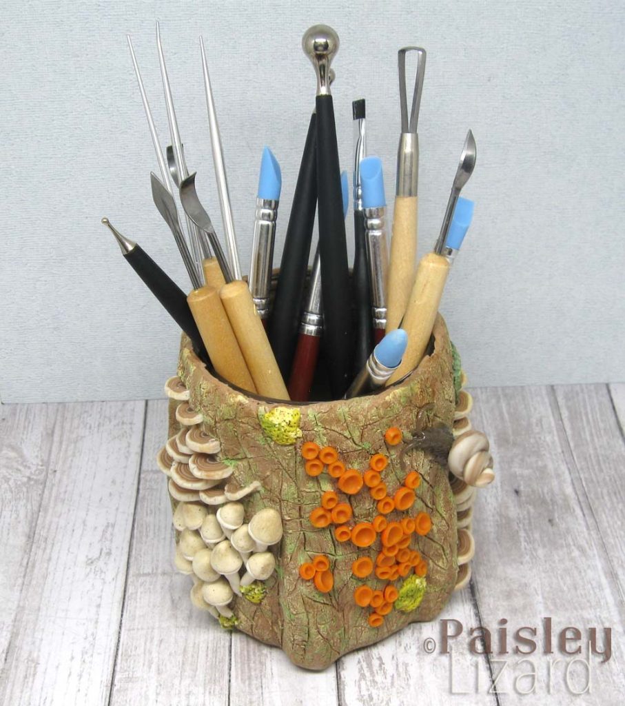 Polymer clay covered "tree stump" jar with sculpting tools.