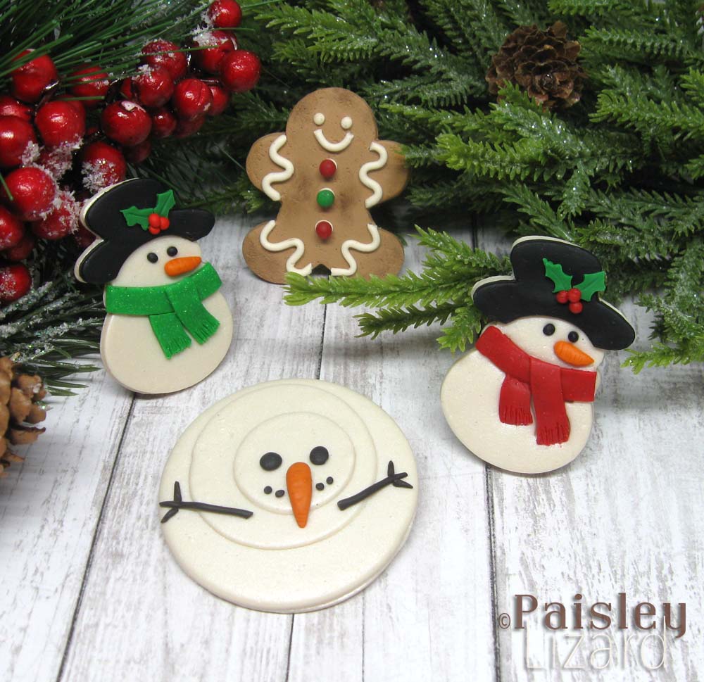 Polymer clay brooches shaped as gingerbread man and snow people.