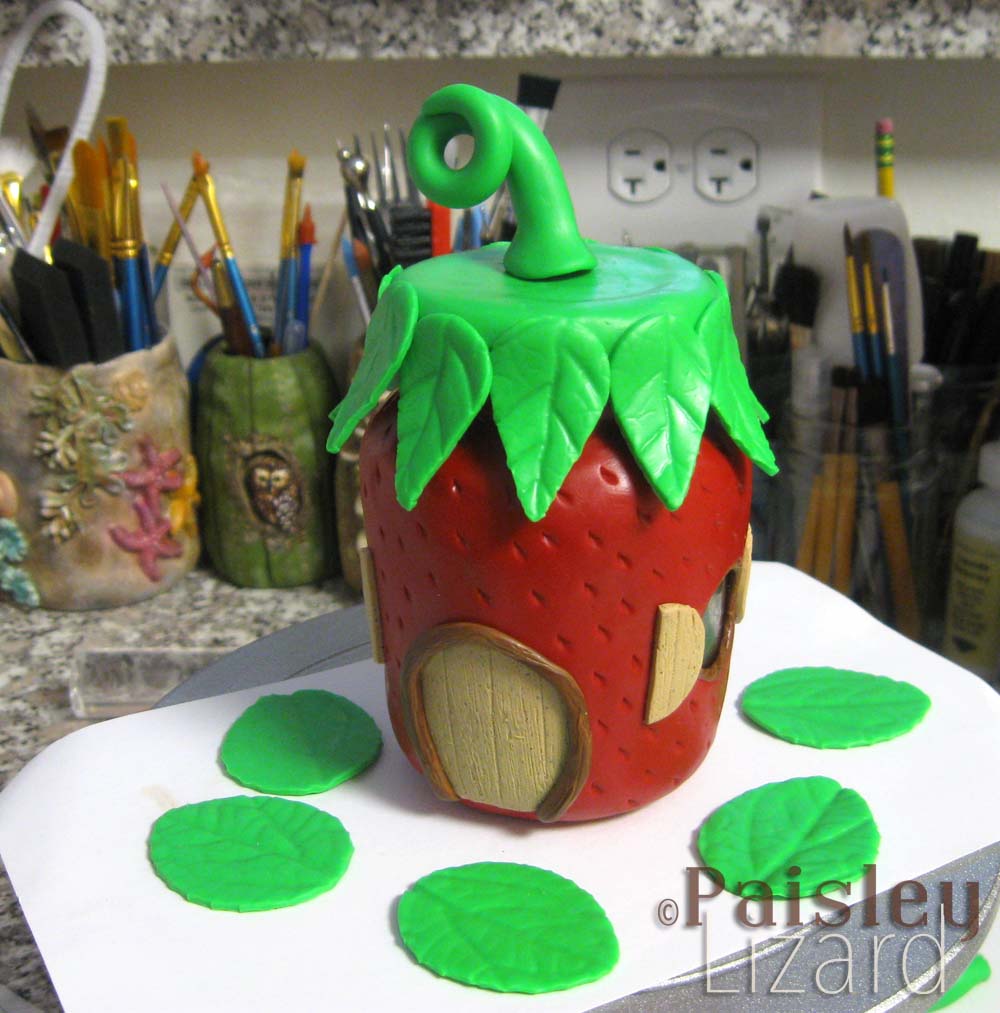 glass jar covered with polymer clay to form strawberry fairy house