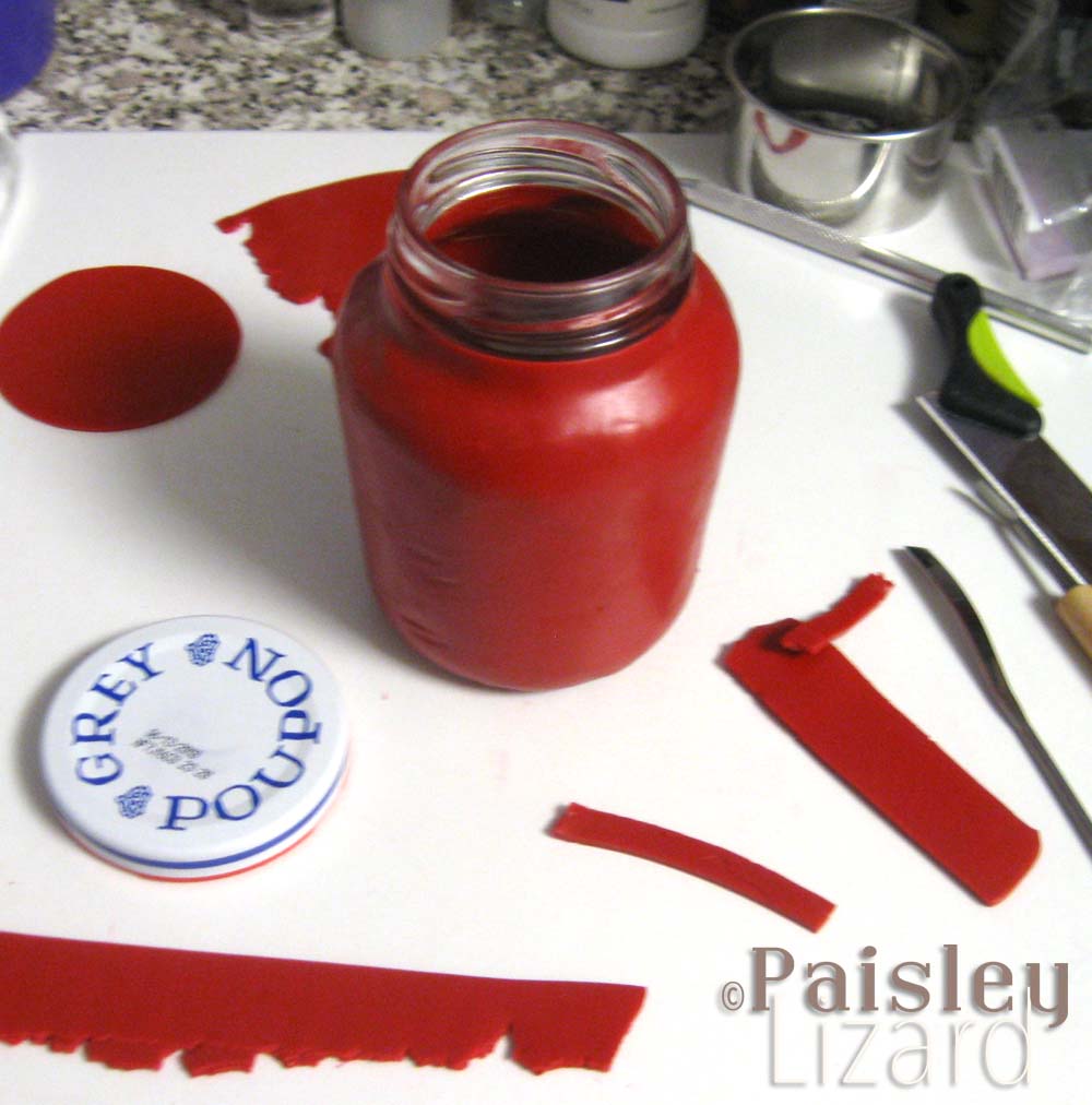 Glass jar being covered with red polymer clay