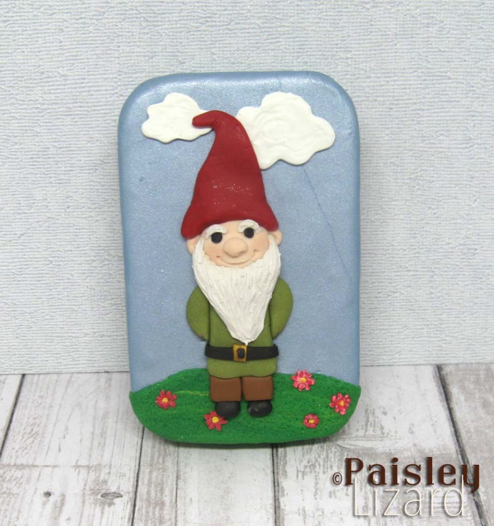 Hinged metal tin with polymer clay gnome on lid.