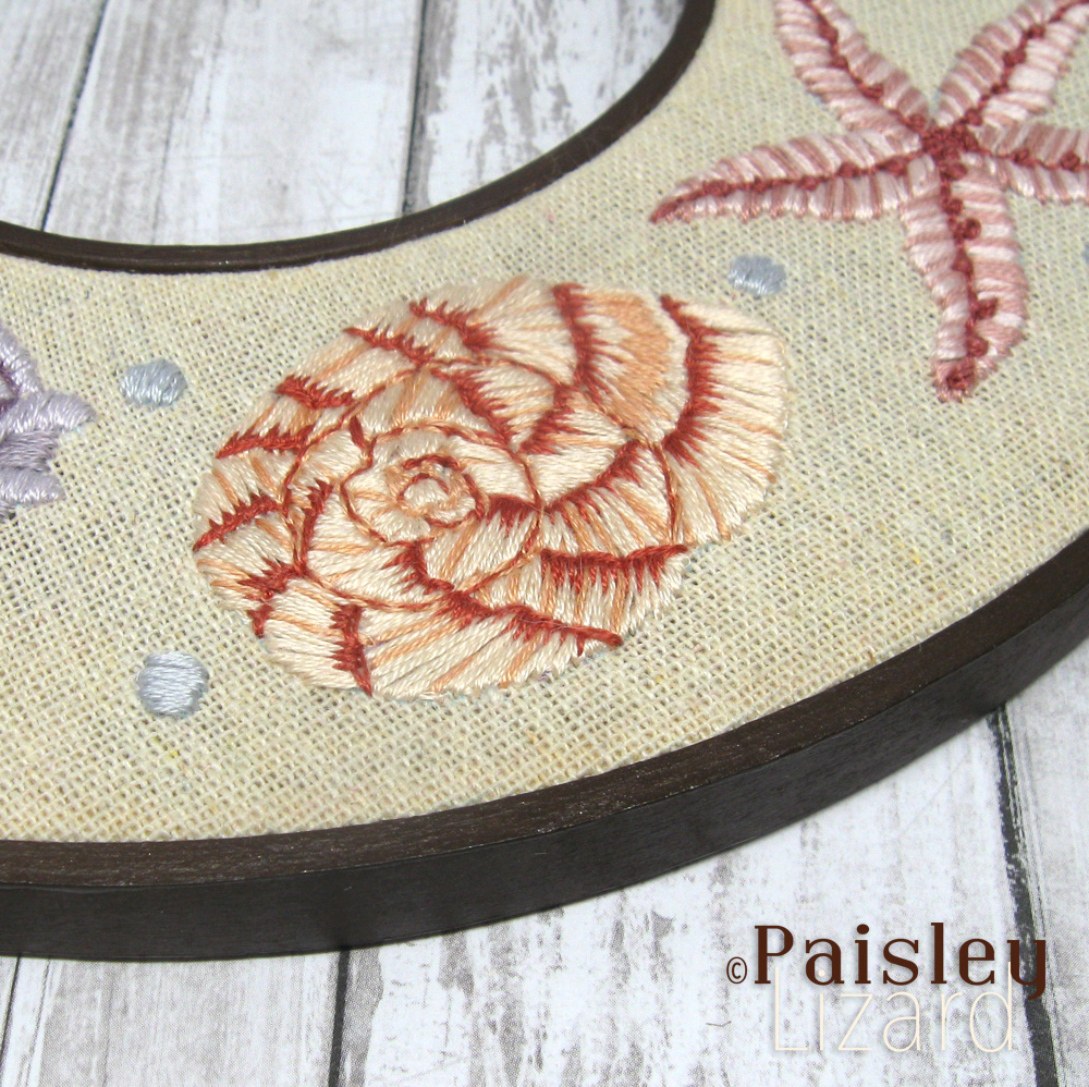 Peach nautilus shell embroidered on beige linen fabric.
