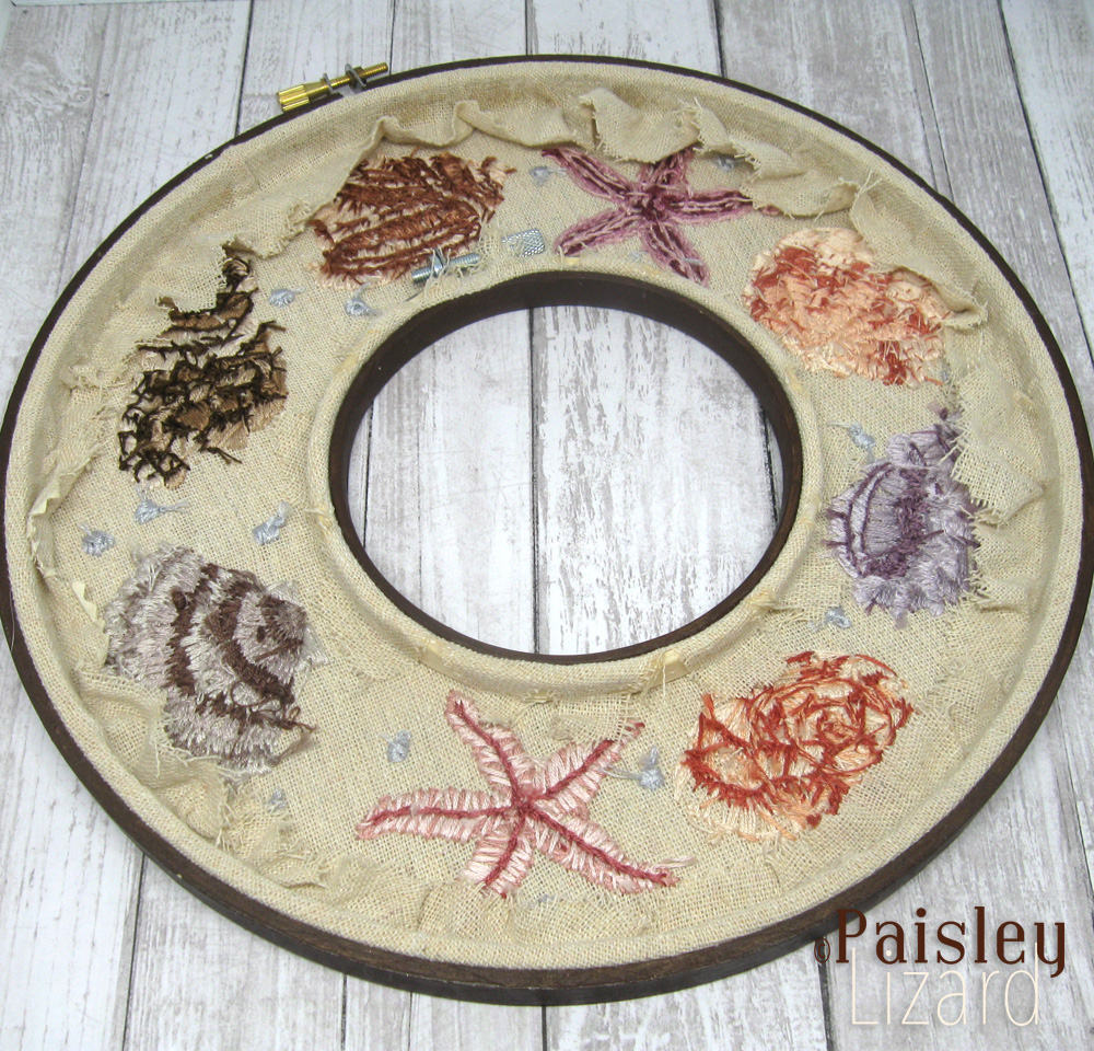 Back view of embroidered seashell wreath on linen fabric.