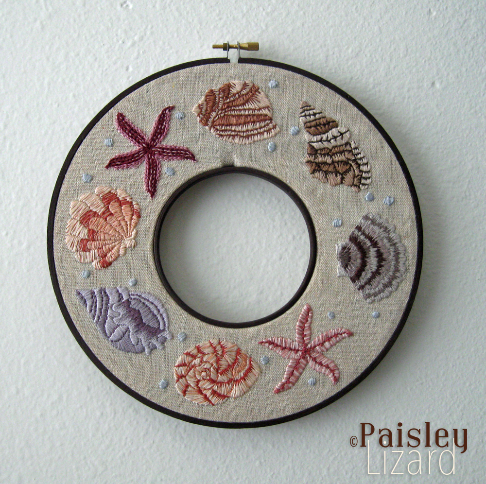 Embroidered seashell wreath hanging on the wall.