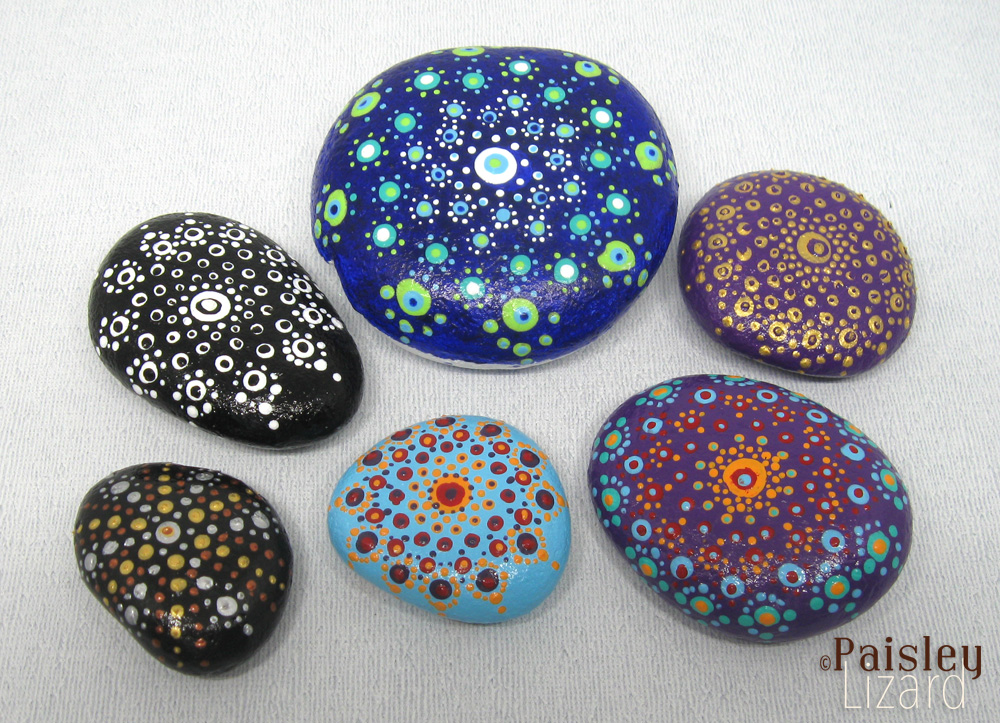 Six stones painted with dot mandalas.